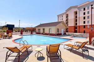 a swimming pool with chairs and a table and buildings at River View Condo Sleeps 6 Shared Hot Tub & Pool in Pigeon Forge
