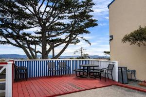 a table and chairs on a deck with a tree at Bay Breeze Inn in Seaside +18 photos