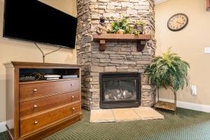a living room with a stone fireplace with a tv at Downtown Summit Manor Sleeps 8 Mtn Views Pool in Gatlinburg +18 photos