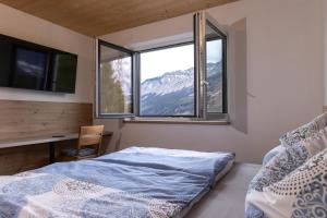 a bedroom with a bed and a desk and a window at Huawa Appartements in Öblarn