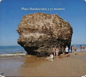a group of people on a beach with a large rock at Bright Apartment AM in Bollullos par del Condado