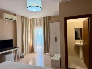 a bedroom with a bed and a sink and a mirror at Hotel Amaiià in Sarandë
