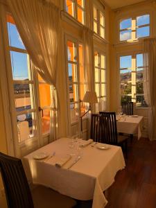 a dining room with two tables with chairs and windows at Hotel Palacio de las Nieves in Langreo +32 photos