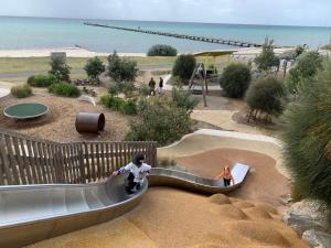 a child on a slide at a playground at Argo Sands, Steps From The Beach! in Rosebud +1 photo