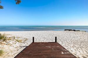 a wooden boardwalk on a sandy beach with the ocean at Argo Sands, Steps From The Beach! in Rosebud