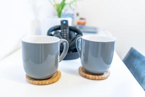 two coffee cups sitting on a counter top at Prestige Guest House Cambridge Modern Ensuite Rooms in Cambridge +61 photos
