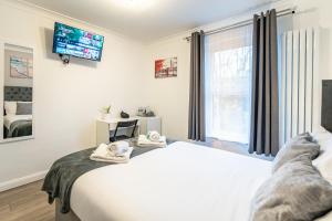 a bedroom with a bed and a tv on the wall at Prestige Guest House Cambridge Modern Ensuite Rooms in Cambridge