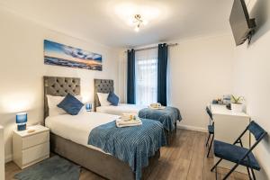 a bedroom with two beds and a table and chairs at Prestige Guest House Cambridge Modern Ensuite Rooms in Cambridge