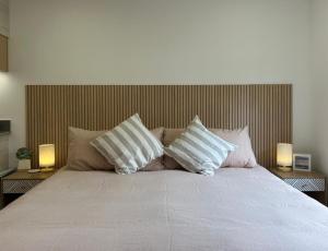 a bed with three pillows and two lamps at Next Door in Punta Arenas