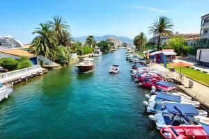 a group of boats docked in a river with buildings at Sol playa piscina in Empuriabrava