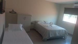 a bedroom with two beds and a window at Litoral suítes in Araruama +10 photos