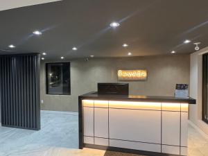 a lobby with a reception desk with a sign on the wall at Ramada by Wyndham Kingston in Kingston