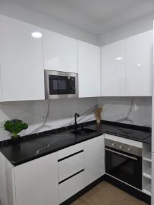 a white kitchen with a sink and a microwave at Bright Apartment AM in Bollullos par del Condado