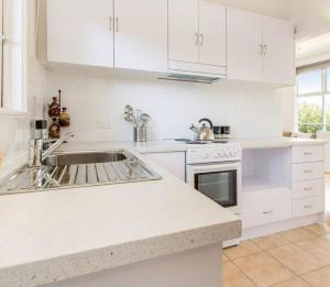 a white kitchen with a sink and a stove at Argo Sands, Steps From The Beach! in Rosebud