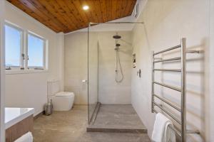 a bathroom with a shower and a toilet at The Black Chalet in Whitianga +34 photos