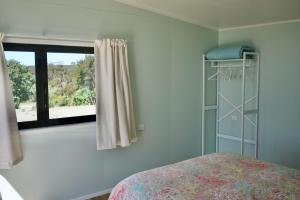 a bedroom with a bed and a window at Estuary Escape in Kaingaroa +6 photos