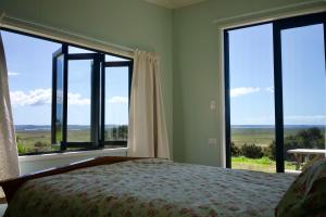 a bedroom with a bed and large windows with a view at Estuary Escape in Kaingaroa