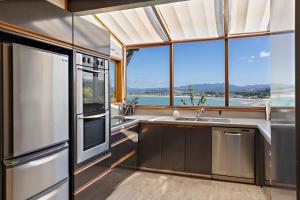 a kitchen with stainless steel appliances and a large window at The Black Chalet in Whitianga