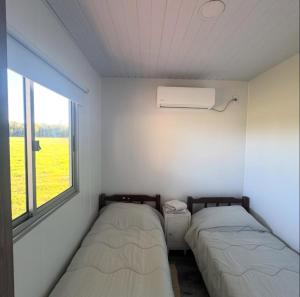 two beds in a small room with a window at Cabañas El Calabrés in Tacuarembó
