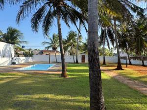a yard with palm trees and a swimming pool at Casa Olivia - Eureka in Atins