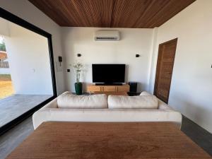 a living room with a white couch and a flat screen tv at Casa Olivia - Eureka in Atins +9 photos