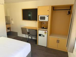a room with a bed and a desk with a microwave at Aspley Motor Inn in Brisbane