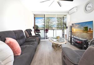 a living room with a couch and a tv at Reddall Waterside Stay in Lake Illawarra