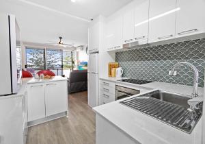 a kitchen with white cabinets and a sink in it at Reddall Waterside Stay in Lake Illawarra