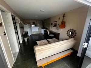 a living room with a couch and a guitar at Studio do Wander in Amparo
