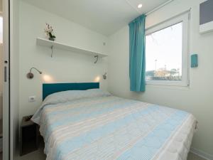 a bedroom with a bed with a blue headboard and a window at great mobile home in Cesenatico in Cesenatico +9 photos