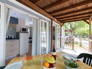 a table with a bowl of fruit and wine glasses at Cozy mobile home in Cesenatico in Cesenatico