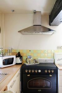 een keuken met een zwarte kachel en een magnetron bij Gite du courtils in Courtils