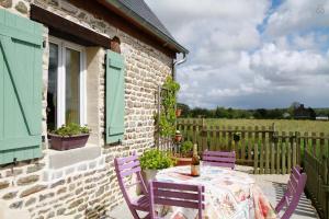 a table with purple chairs on a patio at Gite du courtils in Courtils