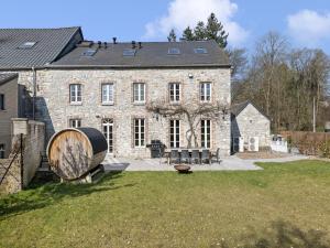 a large stone building with a large barrel in the yard at Mansion in Aywaille with sauna in Aywaille