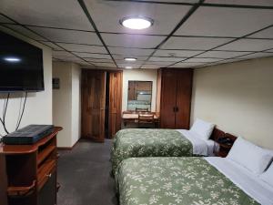 a hotel room with two beds and a television at Hotel Piquellan in Quito