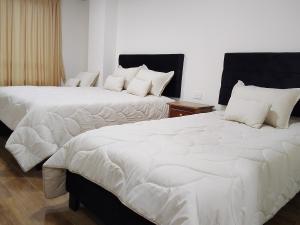 two beds in a room with white sheets and pillows at Hospedaje Santa Barbara in Tabio +3 photos