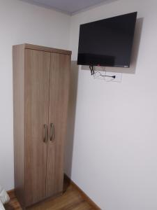 a wooden cabinet with a flat screen tv on a wall at Hospedaje Santa Barbara in Tabio