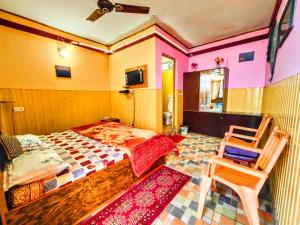 a bedroom with a bed and two chairs in it at Himvadi Resorts Kausani in Kausani +78 photos