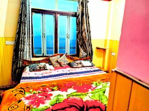 a bedroom with a bed with a floral bedspread and a window at Himvadi Resorts Kausani in Kausani