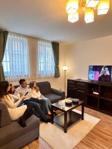 a group of people sitting in a living room watching tv at City-Top Panorama House & Apartments in Esztergom