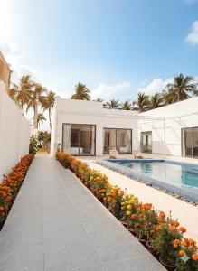 a house with a swimming pool and some flowers at Villa Santoni Mũi Né in Mui Ne