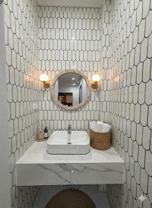 a white tiled bathroom with a sink and a mirror at Villa Santoni Mũi Né in Mui Ne