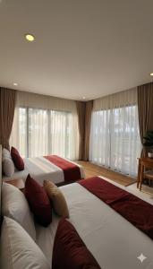 a bedroom with three beds with red and white sheets at Villa Santoni Mũi Né in Mui Ne