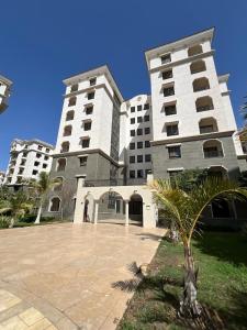 two large white buildings with a palm tree in front at Celia new capital 3 bedrooms in Cairo