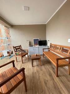 a living room with wooden benches and a tv at Hostel Fratelli Costa in Delfinópolis