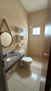 a bathroom with a toilet and a sink and a mirror at Casa familiar no Campestre, tranquila e bem localizada in São Raimundo Nonato