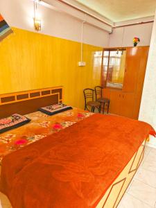a bedroom with a large bed with an orange blanket at Himvadi Resorts Kausani in Kausani