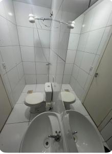 a white bathroom with two toilets and a sink at Pousada 705 Norte 3 in Brasília