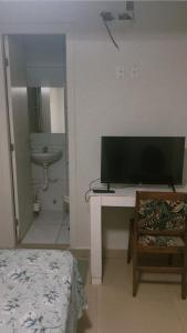 a room with a desk with a television and a bathroom at Pousada 705 Norte 3 in Brasília