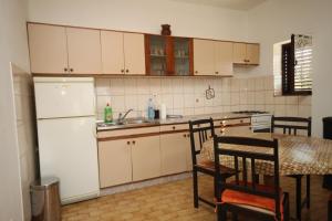 a kitchen with a table and a white refrigerator at Studio Nevidjane 8401a in Neviđane